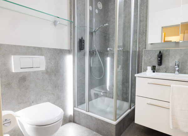 Helles Badezimmer mit weißem Waschtisch und großer Dusche