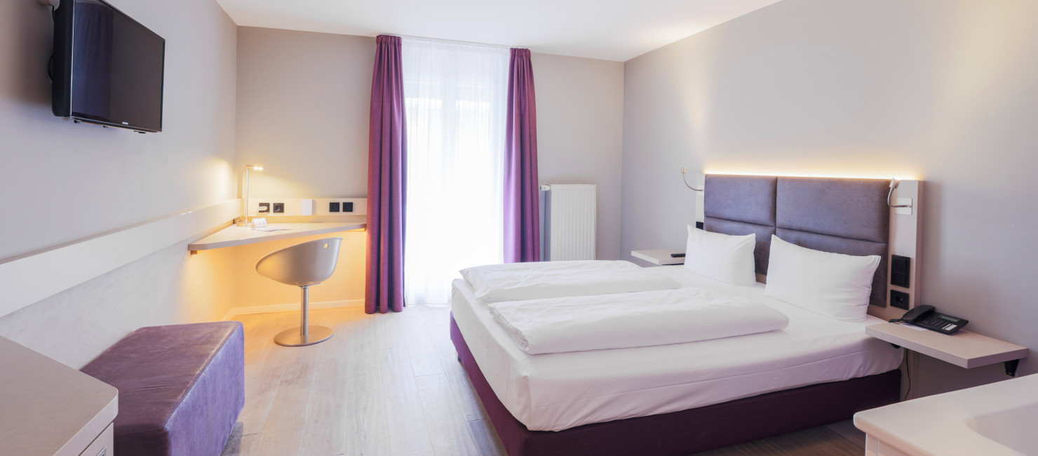 Doppelzimmer mit Terrassenzugang, die Einrichtung ist modern mit Akzenten in Aubergine