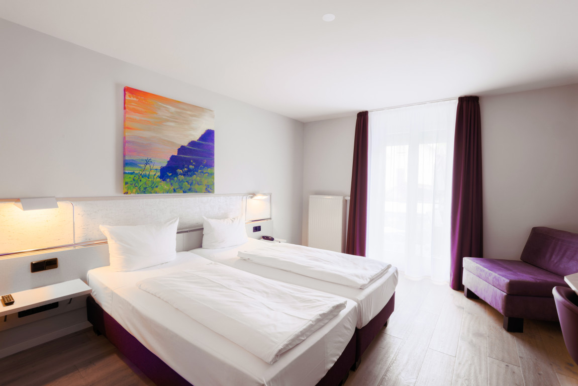 Doppelzimmer mit Balkontüre, hell mit auberginfarbenen Elementen