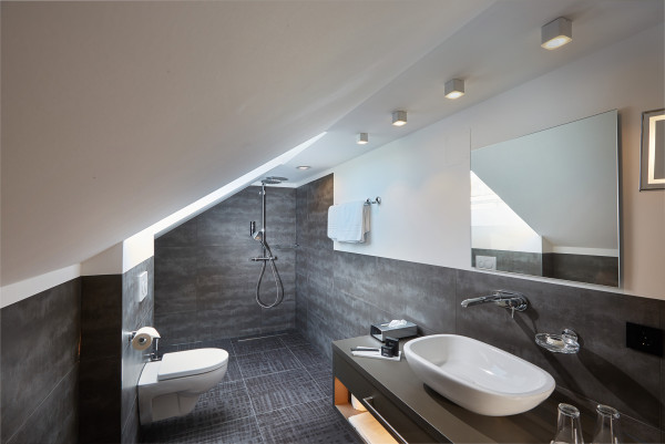 Badezimmer mit Dachschräge und offener Dusche und dunkelgrauen Fliesen