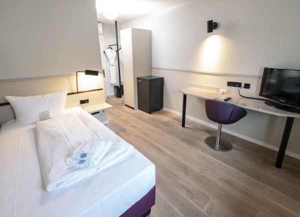 Modernes Zimmer mit Schreibtisch, Einzelbett, und seperatem Badezimmer