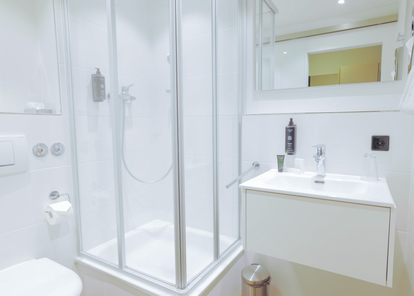 Badezimmer mit Duschkabine, alles in hellem weiß