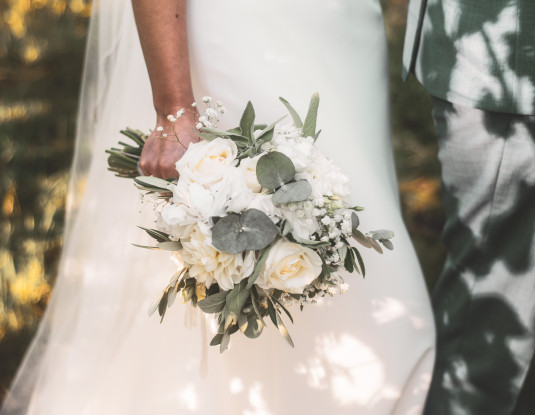 Ausschnitt einer Braut im weißen Brautkleid mit schönem Brautstrauß