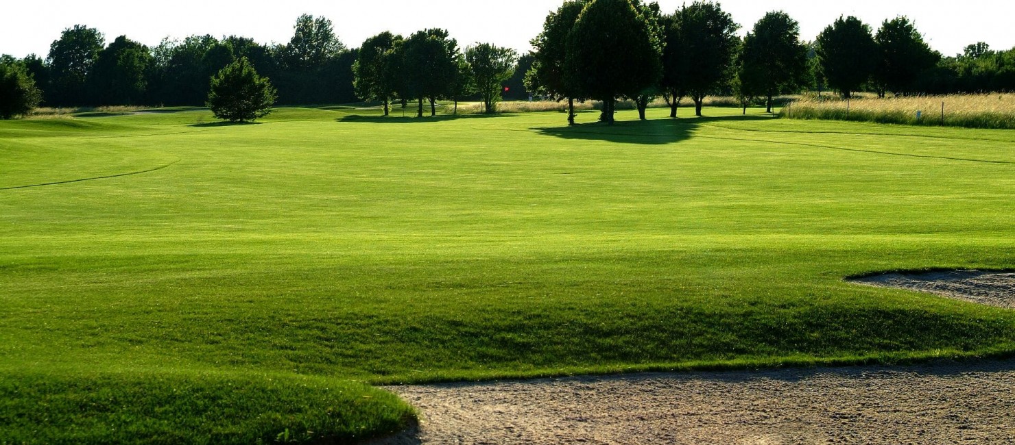 Blick über einen Bunker auf das kurz gemähte Fairway des Golfclubs in der Nähe des Hotel Schloss Reinach