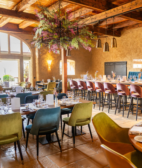 Blick in das moderne Restaurant Cross-over mit Stühlen in türkis, grün und lila Samt, Blick zum Rundbogen nach draußen.