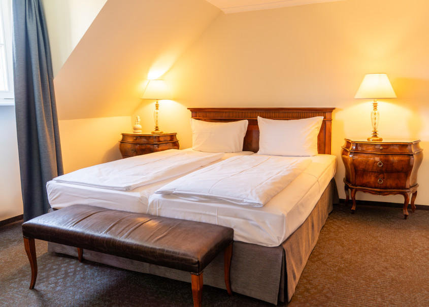 Gemütliches Doppelbett im Zimmer mit rundem Tisch mit Nachttischen im Rokoko Stil