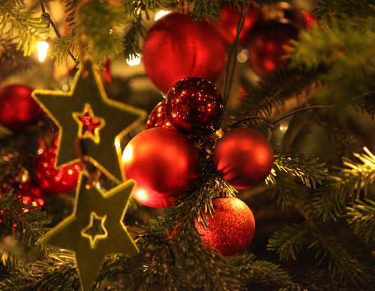 Tannenzweige mir roten Christbaumkugeln, Lichtern und Sternen
