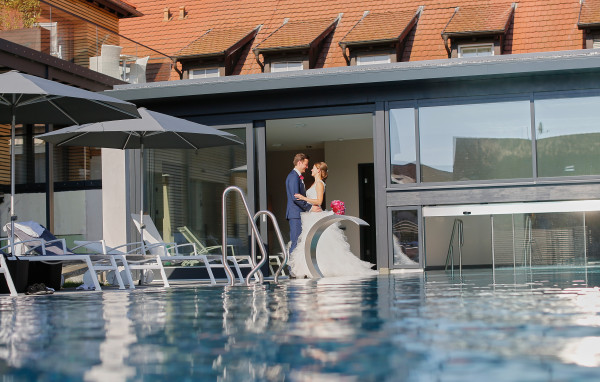 Hochzeitspaar steht am Pool des Hotel Schloss Reinach
