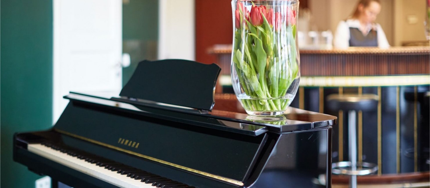 Blick auf ein schwarzes Klavier mit einer großen Vase mit Tulpen 