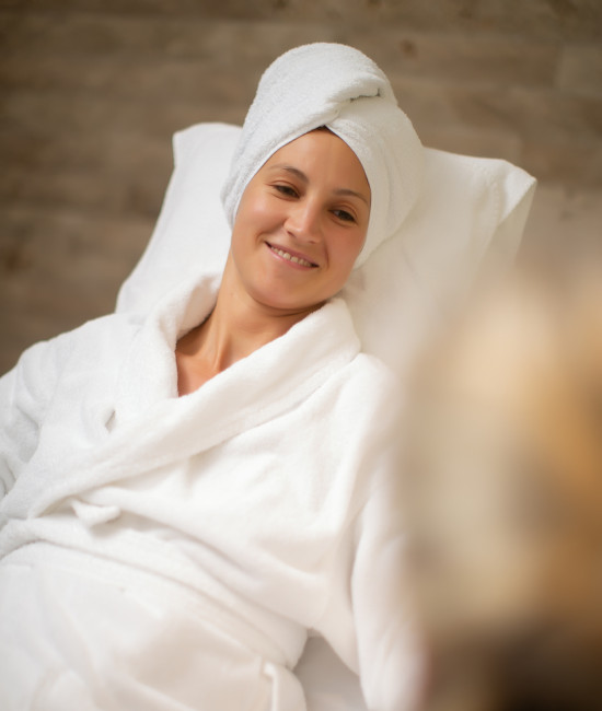 Eine Frau im Bademantel und Handtuch auf dem Kopf genießt eine Anwendung im Wellnesshotel bei Freiburg