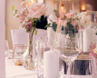 Gedeckter Tisch mit Blumen in zarten rosa Tönen und Gläsern 